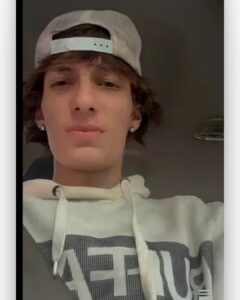 Selfie of a young man in a backwards cap and light hoodie, looking into the camera.